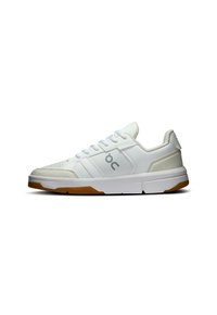 White athletic shoes with suede and mesh panels, featuring a rounded toe, lace-up front, and gum rubber outsole. Logo displayed on side.