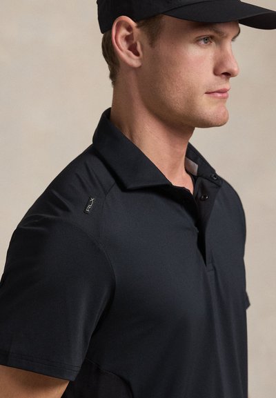 Μαύρο πόλο μπλουζάκι με κουμπωτή λωρίδα, κοντά μανίκια και γιακά, με λογότυπο στο ύψος του ώμου και κομψή υφή υφάσματος.