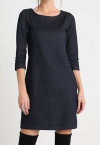 Robe bleu marine, longueur genou, en tissu doux, avec des manches trois quarts et un col rond. Design simple sans motifs ni hardware.