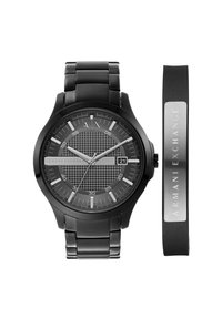 Montre analogique noire avec un cadran noir texturé, des accents argentés et un affichage de la date. Comprend un bracelet en caoutchouc assorti et un bracelet métallique.