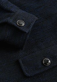 Navy blue textured fabric, featuring two black buttons on cuffs. The material appears soft with a slight sheen and visible threading.