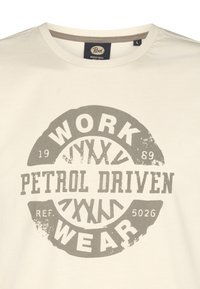 Svetlobéžové tričko vyrobené z bavlny, s kruhovou šedou grafikou a textom "WORK PETROL DRIVEN WEAR" a opotrebovanými detailmi.