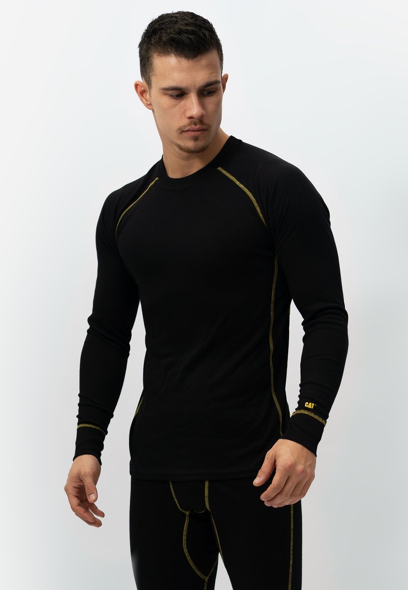 Zwarte langemouwen shirt met gele stiksels, met een ronde hals en een strak ontwerp. Het materiaal lijkt glad en is geschikt voor sportkleding.