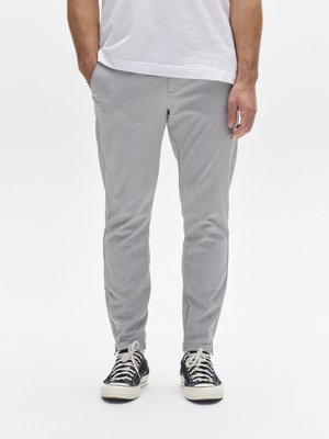 Pantalones gris claro de corte cónico con tejido texturizado, bolsillos frontales y ajuste slim, combinados con zapatillas negras y blancas con cordones.