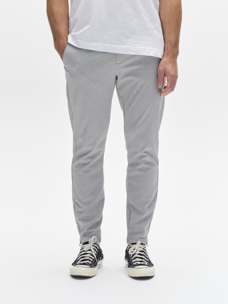 Light gray tapered pants with a textured fabric, front pockets, and a slim fit, worn with black and white sneakers featuring laces.