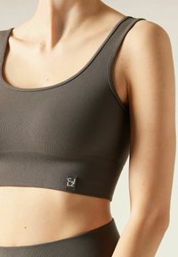 Prążkowany, oliwkowozielony crop top z szerokimi ramiączkami i dopasowanym krojem; posiada małą czarną metkę po lewej stronie.