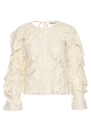 Cremefarvet bluse i blonde med flæser og lange ærmer samt knydebånd ved halsen. Blomstermønster over hele blusen med samlede ærmer og tætsiddende manchetter.