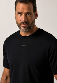 T-shirt nera a maniche corte realizzata in tessuto morbido con colletto tondo. Presenta un discreto logo "JP1880" stampato in grigio sul petto.