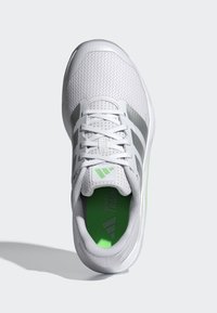 White athletic shoe with mesh upper, grey accents, and green insole. Features six eyelets and flat laces for secure fit.