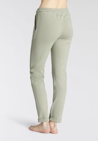 Hellgrüne Jogginghosen mit elastischem Bund und umgeschlagenen Säumen. Sie verfügen über Seitentaschen und haben eine weiche, glatte Textur.