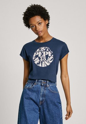 Camiseta de algodón navy con un gráfico circular blanco que dice "EST. PEPE JEANS." Presenta mangas cortas enrolladas y un corte relajado.