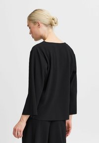 Black ribbed pullover top with a wide neckline and three-quarter length sleeves, displaying a textured pattern and relaxed fit.
