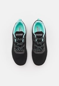 Black athletic shoes with a textured upper, featuring black and turquoise laces, a turquoise interior, and a white sole.