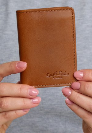 Brown leather wallet with a smooth texture, featuring visible stitching and embossed "Gusti Leder studio" logo on the bottom right.
