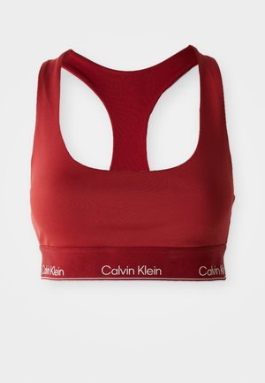 Rode sportbeha met een racerbackontwerp, gemaakt van gladde stof. Heeft een brede band met het "Calvin Klein" logo in het wit.