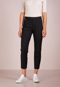 Svarta skräddarsydda byxor med smal passform, tillverkade av slätt tyg. Har en medelhög midjeband och en liten logotypetikett. Kombineras med vita sneakers.