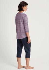 Paars patroon top met driekwartmouwen, gecombineerd met donker marineblauwe cropped broek. Zachte stof en een ontspannen pasvorm.