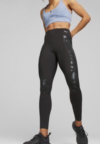 Leggings sportivi neri con accenti lucidi, caratterizzati da una vita alta, un design aderente e pannelli testurizzati sui lati.