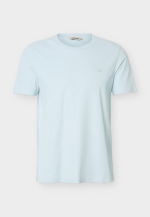 T-shirt bleu clair à manches courtes et col rond avec un logo discret sur le côté gauche de la poitrine, présenté sur un fond clair uni.