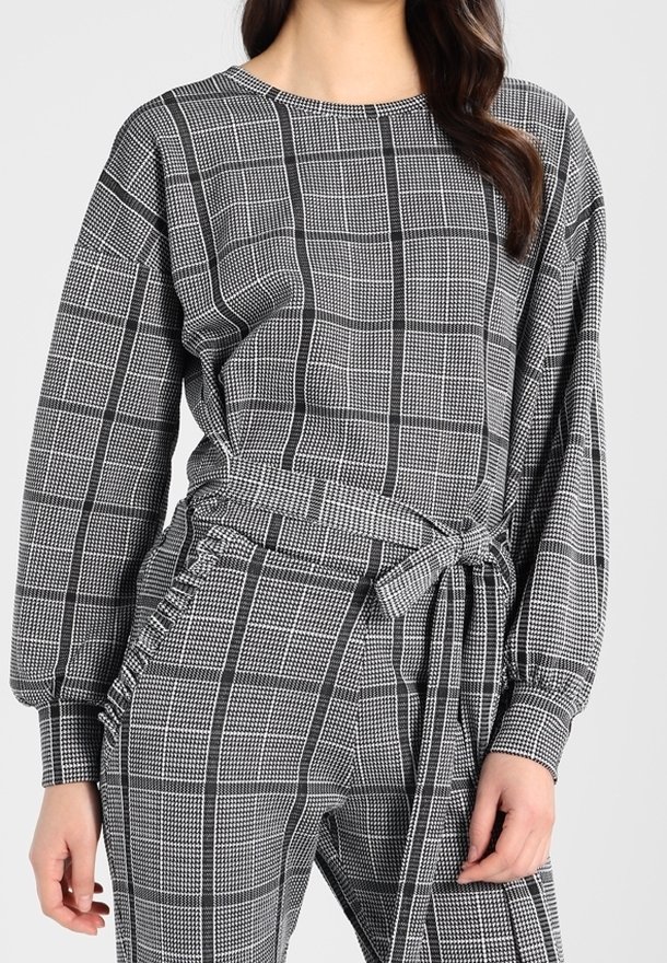 Czarnobiała zestaw loungewear z długimi rękawami, z paskiem w talii i miękką fakturą; wyróżnia się wzorem w kratę i luźnym krojem.