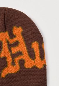 Gorro de punto marrón con un diseño abstracto en naranja y verde, de textura suave y ajuste ceñido, adecuado para clima frío.