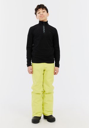 Schwarze Fleece-Zip-Up-Jacke mit hohem Kragen, kombiniert mit leuchtend gelben wasserdichten Hosen und schwarzen Gummistiefeln. Schlichtes und funktionales Design.