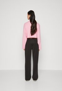 Cropped pink sweater with long sleeves, paired with black wide-leg trousers. Smooth fabric and simple design, minimalistic and modern.