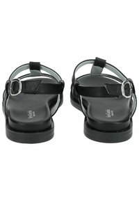 Černé kožené sandály s dekoračními popruhy, nastavitelné přezky na kotníku, plochou podrážkou a hladkým texturovaným vnitřním stélkou. Zadní pohled ukazuje design popruhů.