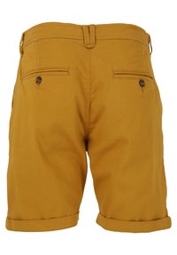 Gula bomullsshorts med en slät yta, som har två bakfickor med knappar och en vikt fåll vid benen.
