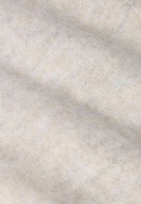 Tissu beige clair doux avec une surface légèrement texturée et des motifs subtils et discrets. Le matériau semble duveteux avec une finition confortable.