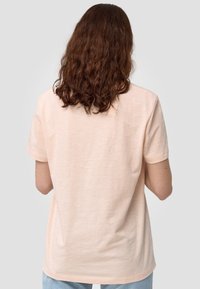 Vaaleanpunainen lyhythihainen t-paita, joka on valmistettu pehmeästä, tekstuurillisesta kankaasta. Paidassa on rento leikkaus ja pyöristetty helma takana.