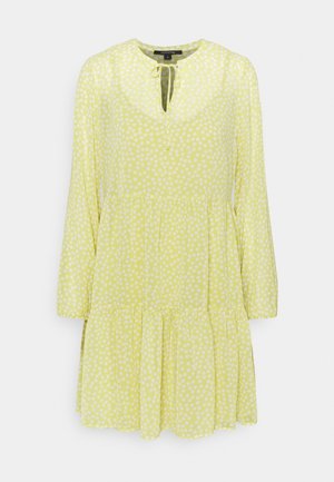 Robe jaune à manches longues avec des pois blancs, jupe à volants, encolure ronde avec ouverture en goutte d'eau et fermeture par lien.