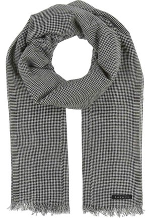 Black and white checkered scarf made of a soft fabric, featuring fringe edges and a label sewn onto one end. Round shape when draped.