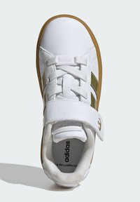 Bijele tenisice s glatkom kožnom vanjštinom, čičak trakama, vezicama, zelenim detaljima i gumenim potplatom. Vidljiv je teksturirani podstavljeni deo.