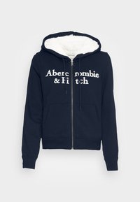 Felpa con zip di colore blu navy con il testo bianco "Abercrombie & Fitch", foderata in morbido pile crema, tasche frontali e polsini e orlo a costine.