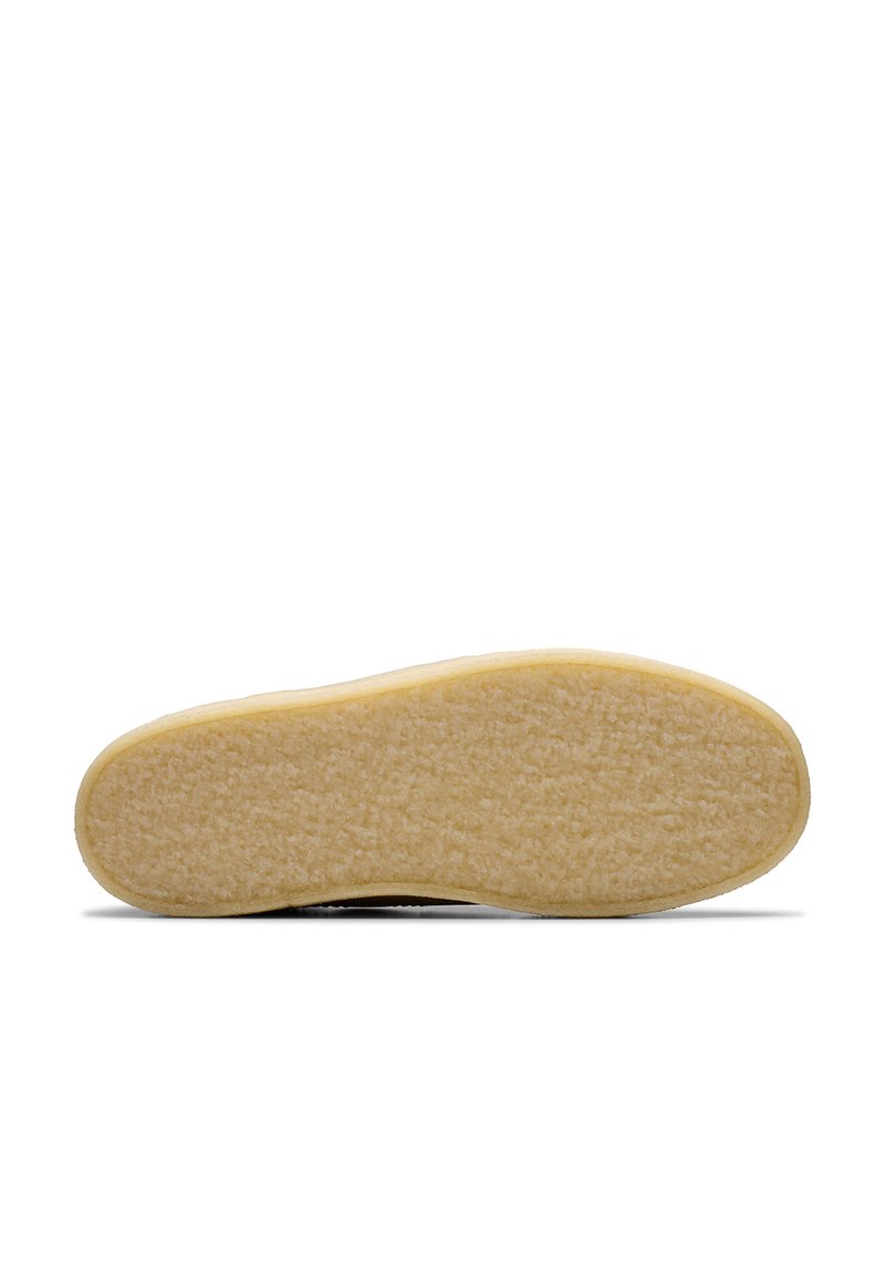 Suola in gomma con superficie texturizzata, caratterizzata da un materiale beige e morbido e da una forma arrotondata, progettata per offrire trazione e durabilità.