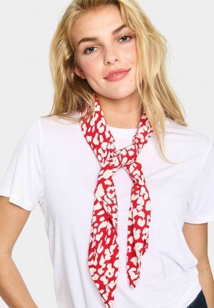 Eșarfă cu un model roșu și alb, dintr-un material ușor, legată într-un nod în jurul gâtului, completând un tricou alb simplu.
