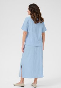 Light blue co-ord set featuring a textured short-sleeve top and a long skirt with a side slit, made from a lightweight fabric.