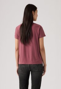 Μπλουζάκι κοντομάνικο από βαμβάκι σε χρώμα σκουρό ροζ με άνετη εφαρμογή. Η πίσω όψη δείχνει λεία υφή και διακριτικές ραφές. Συνδυάζεται με σκούρο τζιν.