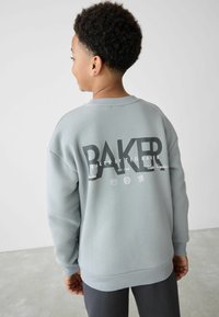 Grå, blød sweatshirt med rund hals, der pryder en iøjnefaldende sort "BAKER" grafik og små logoer på ryggen. Løs pasform, ribbede manchetter.