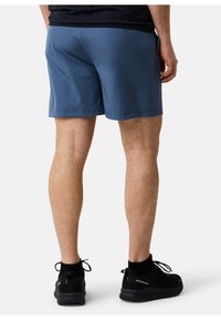 Blå träningstights med en slät yta, knälängd och elastisk midja, kombinerat med svarta, lätta sneakers.