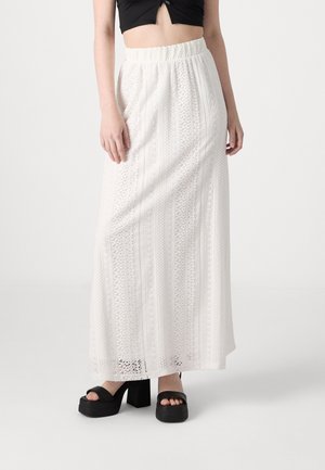 Hvid maxi-nederdel med indviklet blonde mønster, elastisk talje og let tekstur. Båret med sorte platform-sandaler.