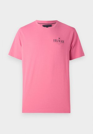 Różowy t-shirt z krótkim rękawem i okrągłym dekoltem, z małym logo "Hilfiger New York 1985" nadrukowanym na lewej części klatki piersiowej.