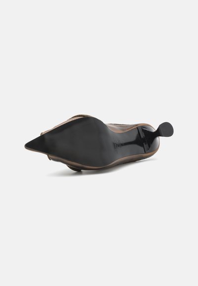 Zapato plano negro de punta afilada con una suela lisa y brillante y un exterior texturizado. Presenta un diseño minimalista y un lazo para facilitar el calzado.