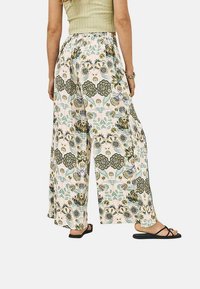 Pantalones de pierna ancha con estampado floral que presentan un fondo pastel claro, patrones de flores en verde oscuro y azul, y una cinturilla elástica para mayor comodidad.