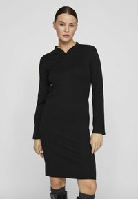 Črna obleka z dolgimi rokavi z rebrasto teksturo, osnovnim ovratnikom in gumbnim okrasjem spredaj. Slim fit dizajn, do kolen.