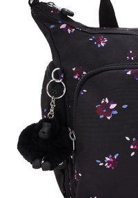 Borsa di stoffa nera con motivo floreale in viola e rosa, dotata di una tasca con zip e un portachiavi a forma di gorilla nero peloso.