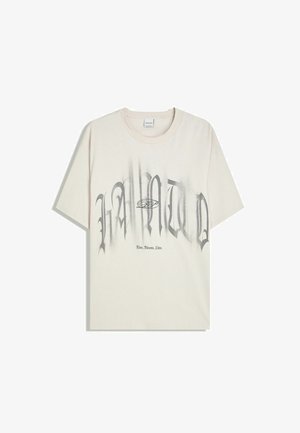 Cremefarvet bomulds-t-shirt med fed sort graffiti-inspireret skrift med gradienter og et cirkulært grafisk motiv. Kortærmet og med rund hals.