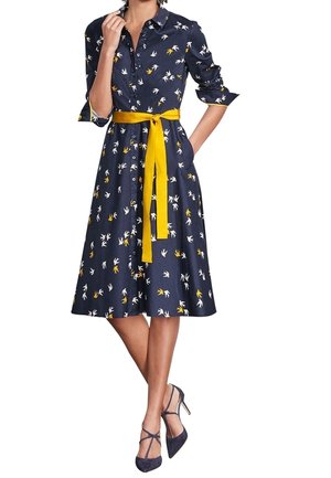 Laivastonsininen puuvillainen kesämekko, jossa on keltainen vyö, nappikiinnitys edessä ja valko-keltaiset kukkakuviot. Midipituisuus ja vyötäröltä istuva malli.