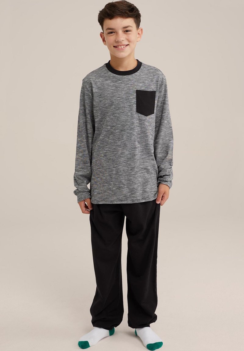 Siva dolgi rokav s črno žepom, v kombinaciji s črnimi hlačami. Udobna, sproščena oblačila za prosti čas, z rebrastimi manšetami in nogavicami z zelenimi poudarki.
